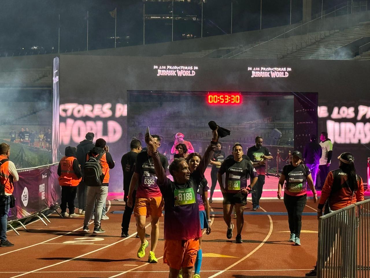 Carrera nocturna en estadio con pantallas LED y corredores